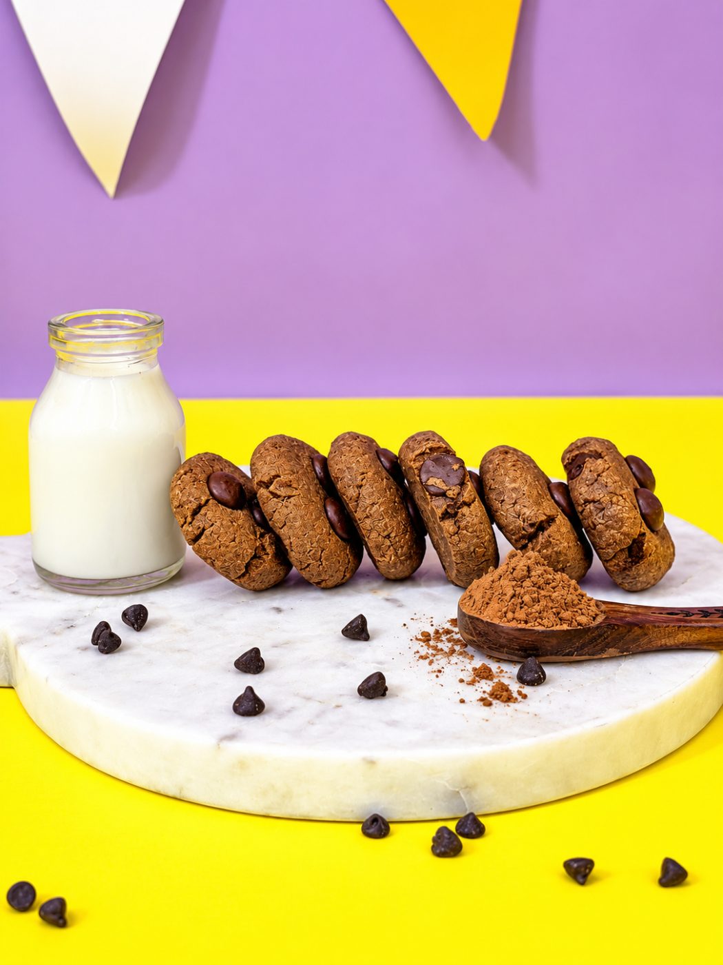 Ragi chocolate chunk cookies on a marble board with milk and cocoa